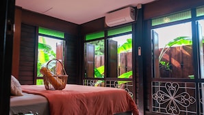 Una habitación con cama, ventana con vistas a zonas verdes y aire acondicionado.