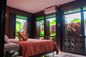 Una habitación con cama, ventana con vistas a zonas verdes y aire acondicionado.