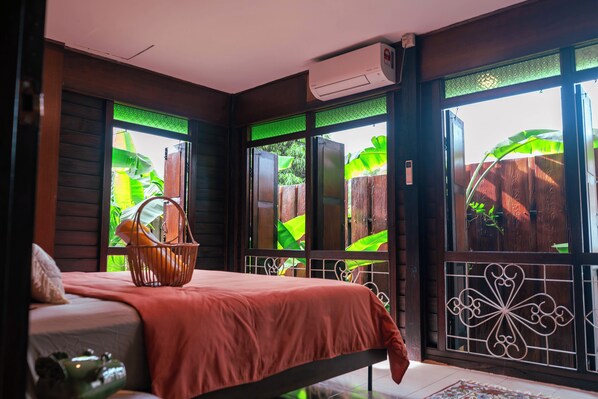 Une chambre avec un lit, une fenêtre donnant sur un espace verdoyant et un appareil de climatisation.
