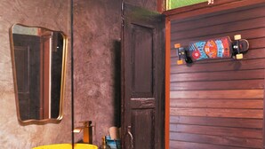 Un baño con puerta de madera, un lavabo amarillo y un espejo.