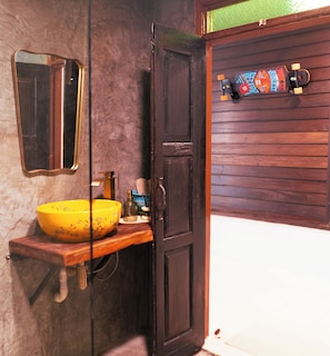 Un baño con puerta de madera, un lavabo amarillo y un espejo.