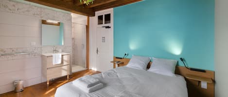 Ein Schlafzimmer mit einem großen Bett, einem Holzkopfende, einem Nachttisch und einer hängenden Pflanze.