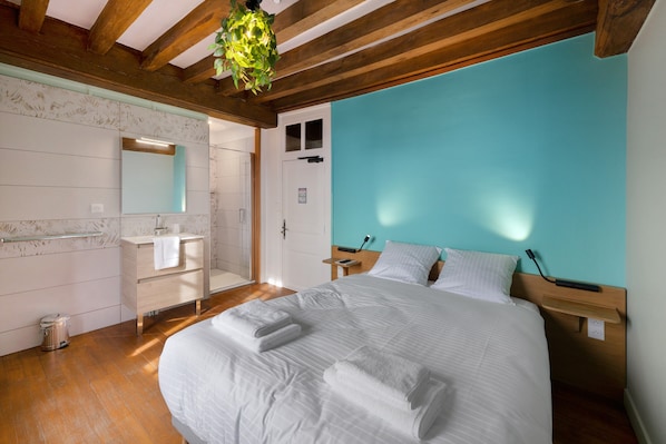 Ein Schlafzimmer mit einem großen Bett, einem Holzkopfende, einem Nachttisch und einer hängenden Pflanze.
