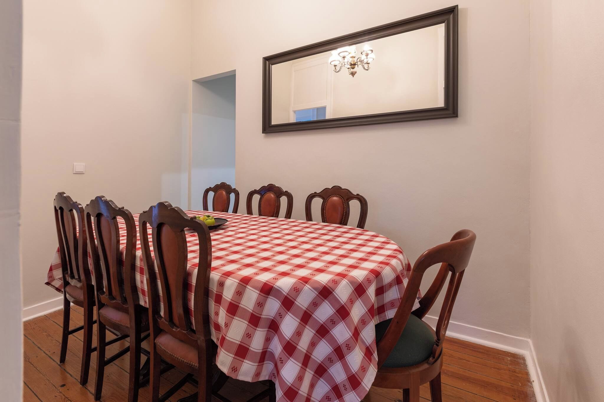 A dining area with a table set for four, surrounded by wooden chairs with cushioned seats.