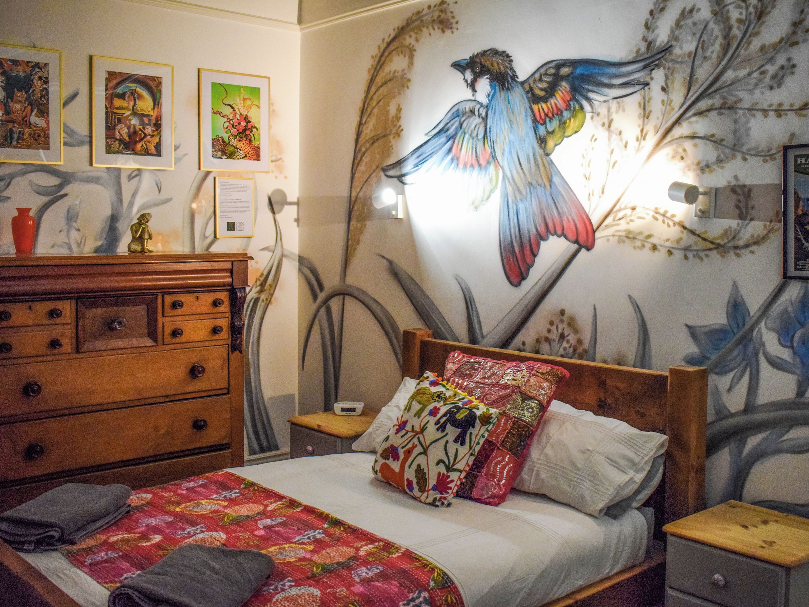 Un dormitorio con cama, cómoda y un mural en la pared.
