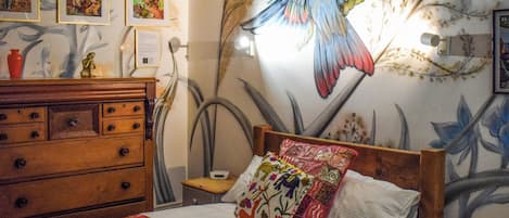 Un dormitorio con cama, cómoda y un mural en la pared.