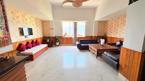 A spacious living area with a sofa set, a coffee table, and a TV mounted on the wall. - Hotel Red Orchid  (Gangtok)