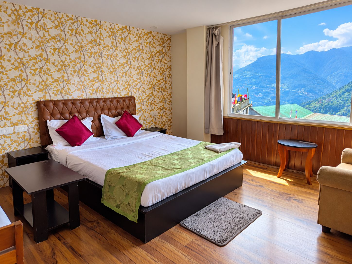 Un dormitorio con una cama, mesitas de noche, vistas a montañas y una ventana con cortinas.