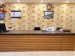 A reception desk with a clock, framed picture, and a travel desk with books. - Hotel Red Orchid  (Gangtok)
