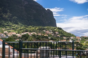 A coastal village with houses on a hillside, a prominent cliff, and a clear sky. - GuestReady - Quinta A Lealdade (Arco de São Jorge)