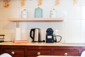 A kitchen counter with a coffee maker, a kettle, and labeled containers for coffee, tea, and sugar. - GuestReady - Quinta A Lealdade (Arco de São Jorge)