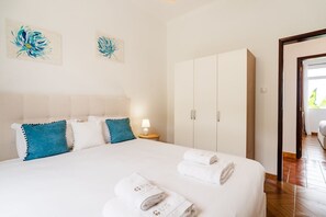 A hotel room with a bed, pillows, a nightstand, a lamp, a wardrobe, and artwork on the wall. - GuestReady - Quinta A Lealdade (Arco de São Jorge)