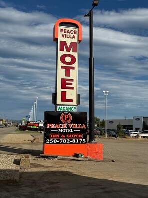 Une enseigne de motel indiquant « Peace Villa Motel » et « Chambres disponibles », ainsi qu’un numéro de téléphone.