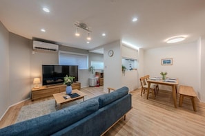 Ein modernes Wohnzimmer mit einer Couch, einem Fernseher und einem Essbereich.