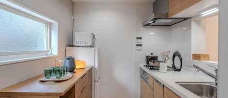 A compact kitchen with a microwave, stove, sink, and wooden cabinets.