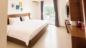A modern hotel room with a large bed, a flat-screen TV, a coffee maker, and a balcony with curtains. - Moc An Collection - Mermaid Seaside VT (Vung Tau)