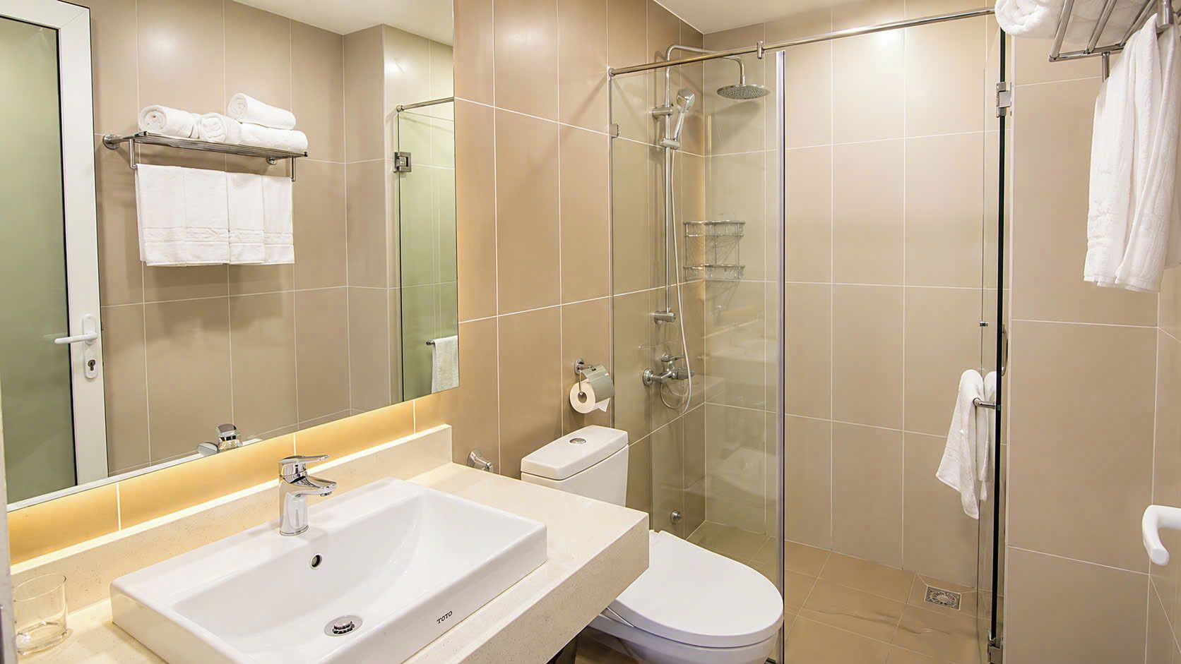A modern bathroom with a glass-enclosed shower, a white sink, and a toilet.