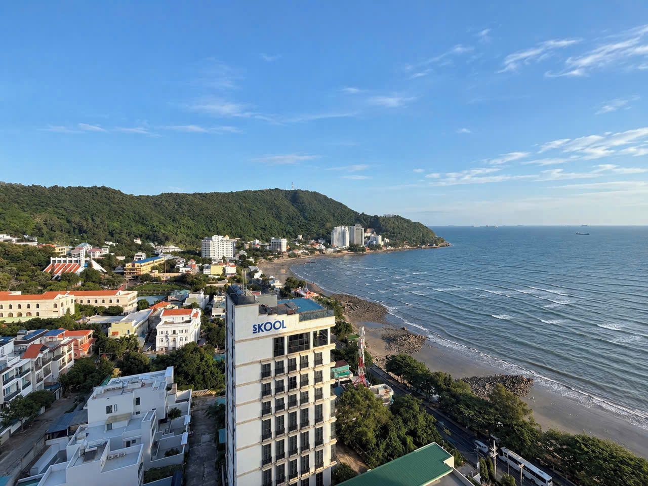 Un paysage urbain côtier avec des bâtiments, une plage et un ciel dégagé.