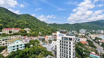 A multi-story building with a prominent 'SKOOL' sign, surrounded by residential buildings and lush greenery.