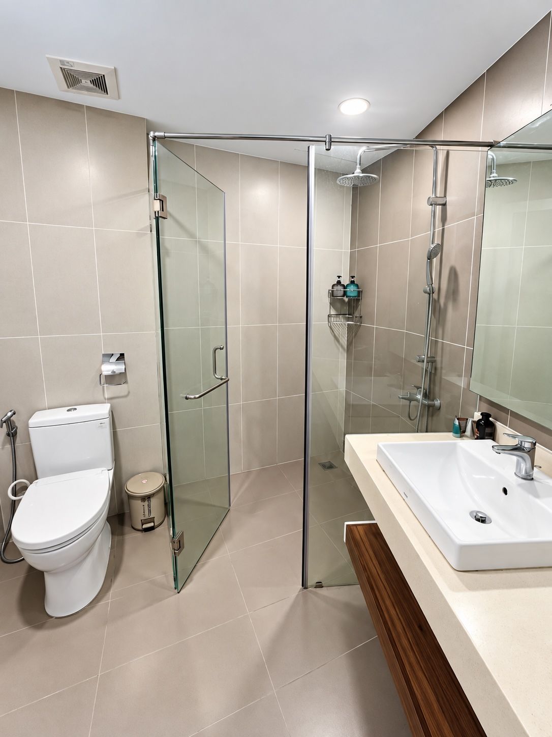 A modern bathroom with a glass-enclosed shower, a white toilet, and a large sink with a mirror above it.