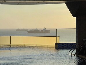 An infinity pool with a view of the sea and a ship in the distance. - Moc An Collection - Mermaid Seaside VT (Vung Tau)