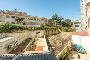 Eine Dachterrasse mit Betonmauer, Pflanzgefäßen und einem Fahrrad.