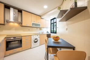 Eine moderne Küche mit eingebauten Geräten, ein Essbereich mit Tisch und Stühlen sowie ein Fenster, das natürliches Licht hereinlässt.