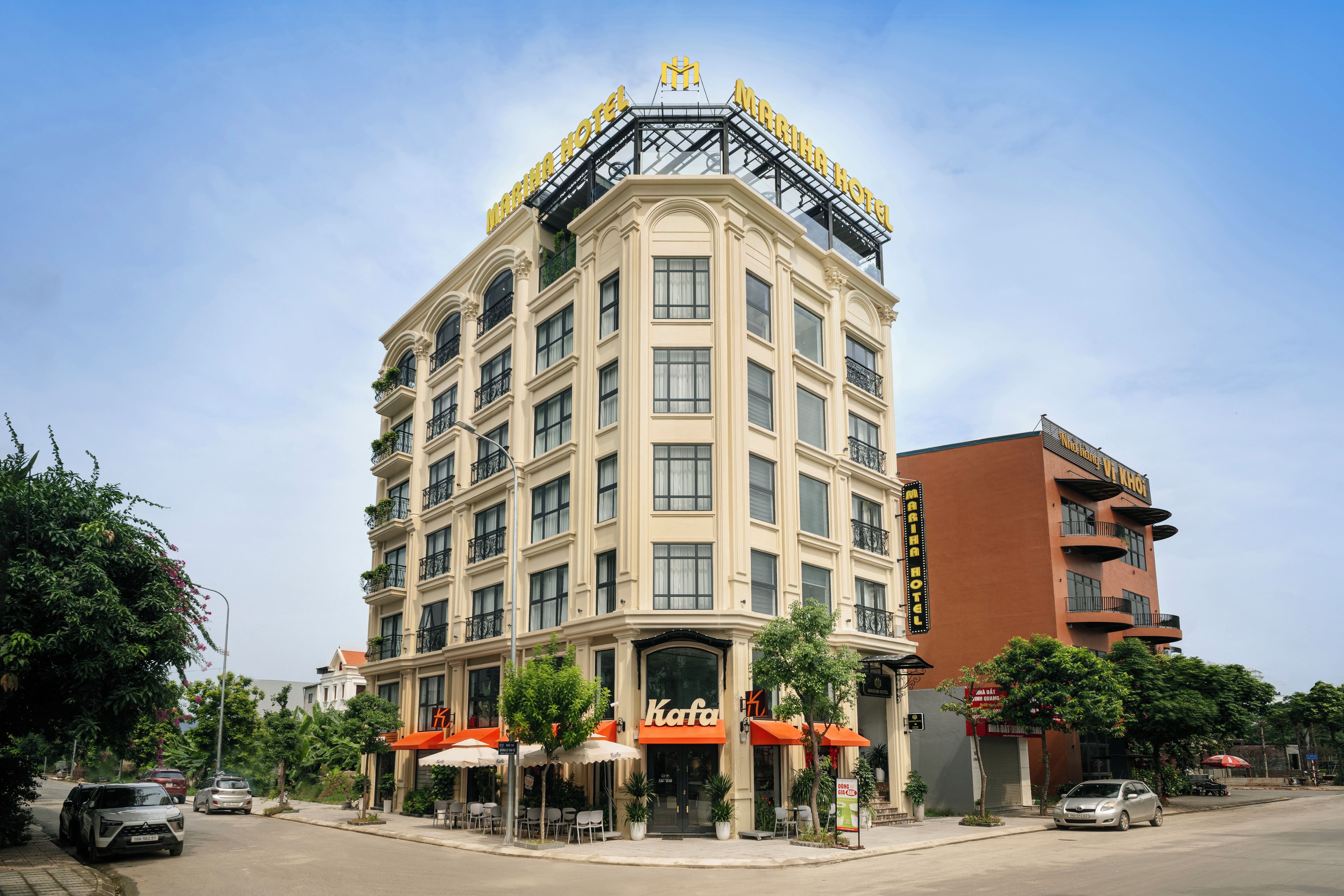 A multi-story hotel with a prominent sign, outdoor seating, and a parking lot.