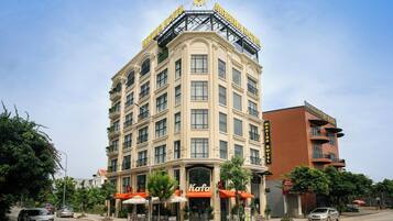 A multi-story hotel with a prominent sign, outdoor seating, and a parking lot.