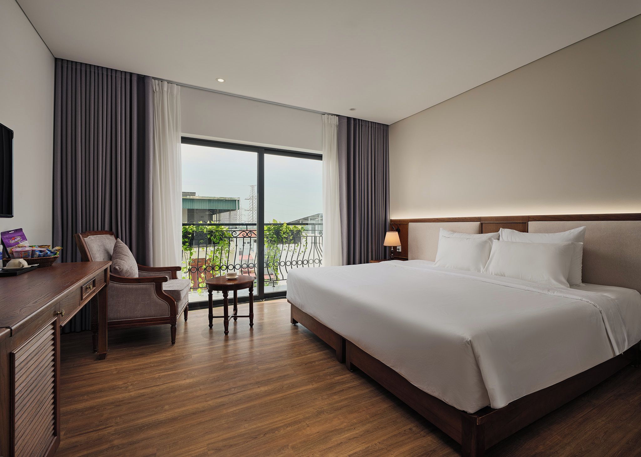 Habitación de hotel con una cama grande, un escritorio, una silla y vistas al exterior.