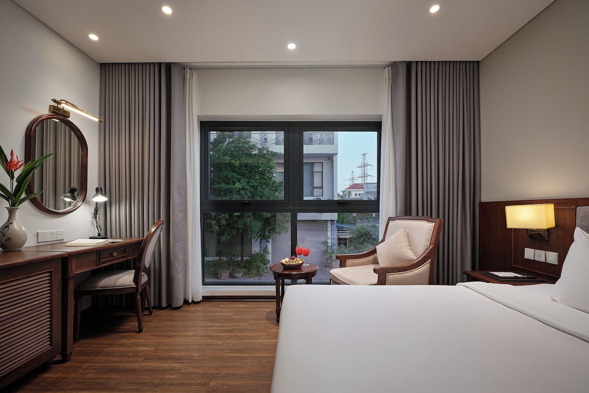 Habitación de hotel con cama, escritorio, silla y vista al exterior.