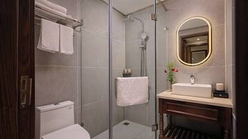 Een moderne badkamer met een douchecabine van glas, een wit toilet, een wastafel met spiegel en een wasbak.