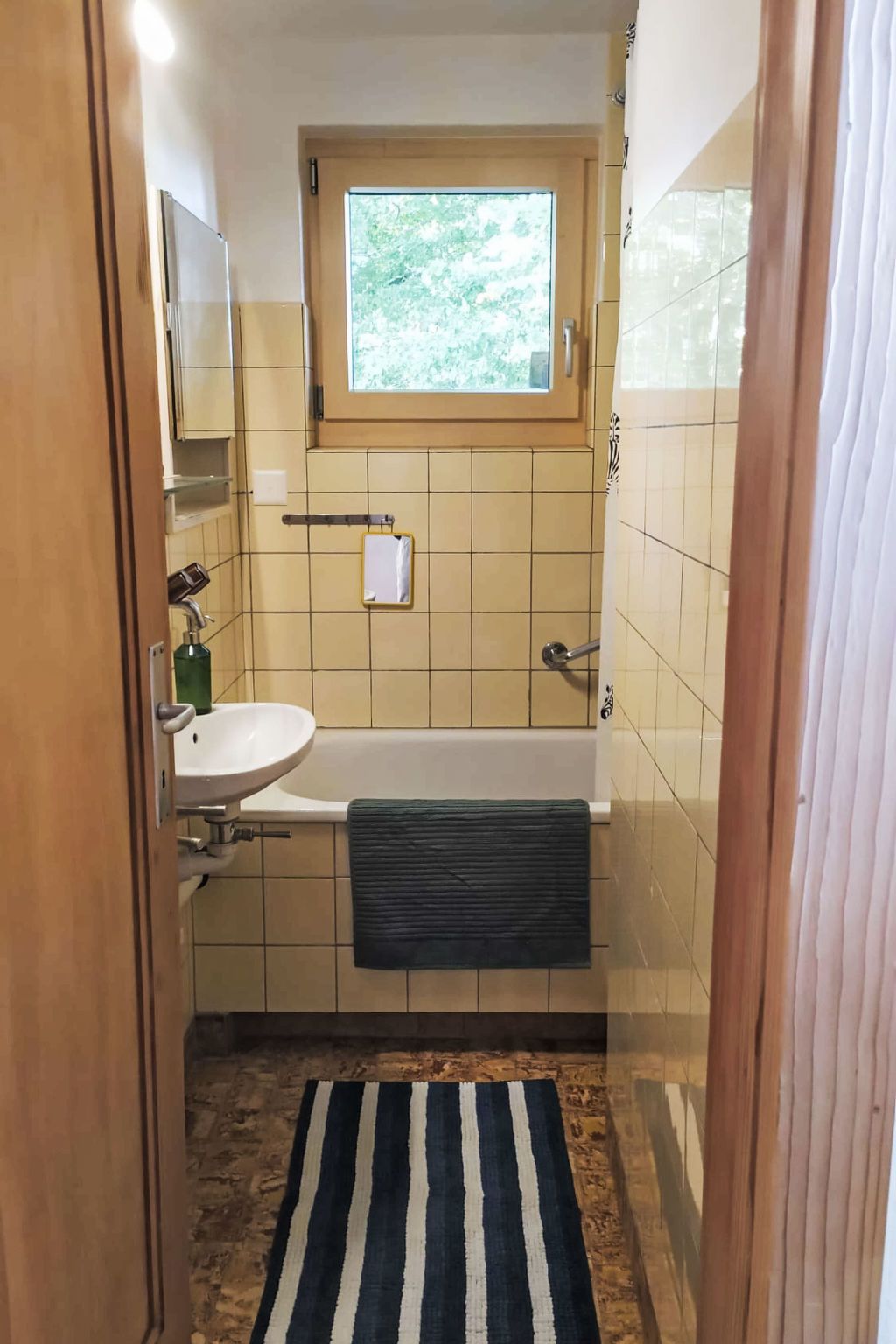 Une salle de bain avec une fenêtre, un lavabo, une baignoire et un porte-serviettes.