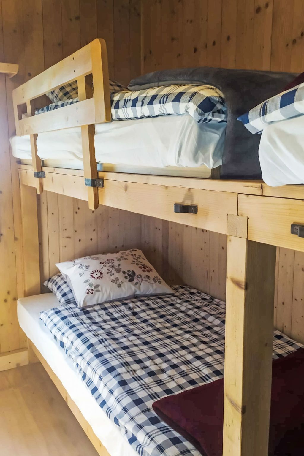 Un lit superposé composé d’un lit inférieur et d’un lit supérieur, tous deux dotés de draps à carreaux.