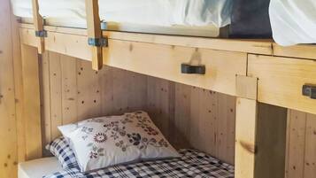 Un lit superposé composé d’un lit inférieur et d’un lit supérieur, tous deux dotés de draps à carreaux.