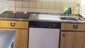 A kitchen with wooden cabinets, a stainless steel sink, and a dishwasher. - Les Fougères by Interhome (Champoz)