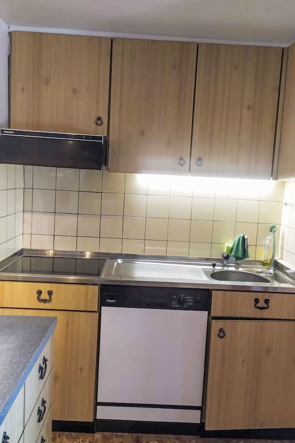 A kitchen with wooden cabinets, a stainless steel sink, and a dishwasher.