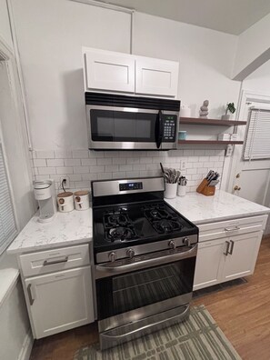 A kitchen with white cabinets, a stainless steel microwave, a gas stove, and a built-in oven.