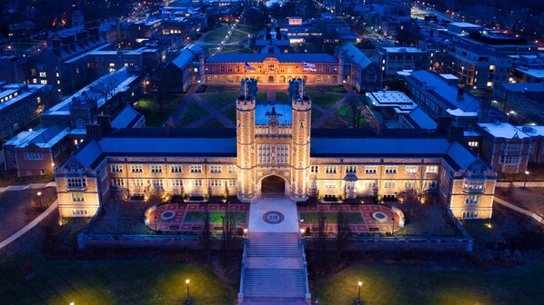 A large, historic building with a central tower, symmetrical facade, and a courtyard with a circular design.