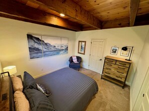 Een slaapkamer met een bed, een kaptafel, een stoel en een schilderij aan de muur.