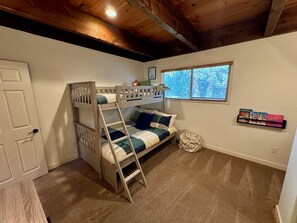 A bunk bed with a ladder, a window with blinds, and a shelf with children's books. - Unique and Spacious Home in Quiet NW Bend - King & Queen Beds - Large Yard (Bend)