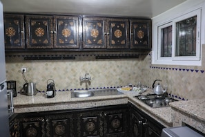 A kitchen with dark wooden cabinets, a granite countertop, a sink, a stove, and a window. - The Riad Kenyandha - Fiber Optics · Swimming Pool · Italian Oven (Marrakech)