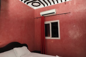 A room with a bed, a window with a curtain, and an air conditioning unit mounted on the wall. - The Riad Kenyandha - Fiber Optics · Swimming Pool · Italian Oven (Marrakech)