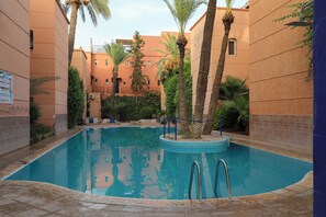 A swimming pool surrounded by palm trees and a building with a tiled exterior. - The Riad Kenyandha - Fiber Optics · Swimming Pool · Italian Oven (Marrakech)