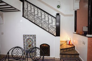 A staircase with ornate metal railings, a patterned tile wall, and a small table with chairs. - The Riad Kenyandha - Fiber Optics · Swimming Pool · Italian Oven (Marrakech)