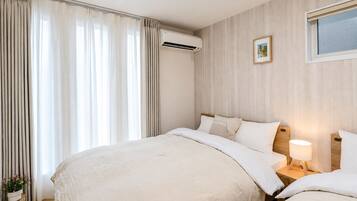 A hotel room with a large bed, a bedside table with a lamp, and an air conditioning unit.