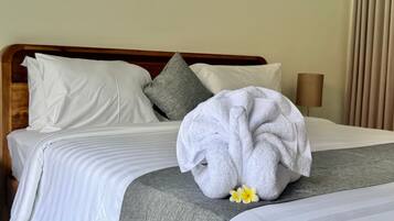 Una cama bien hecha con sábanas blancas, una almohada gris y una toalla con un estampado floral.