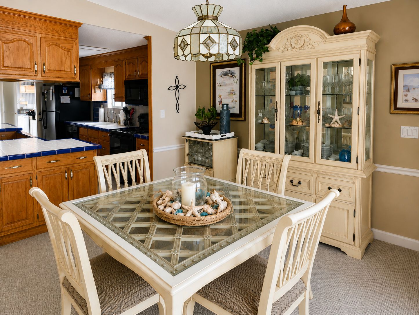 Un coin repas avec une table à plateau en verre, des chaises en osier et un élément décoratif central.