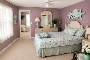 Quarto com cama, penteadeira e ventilador de teto.