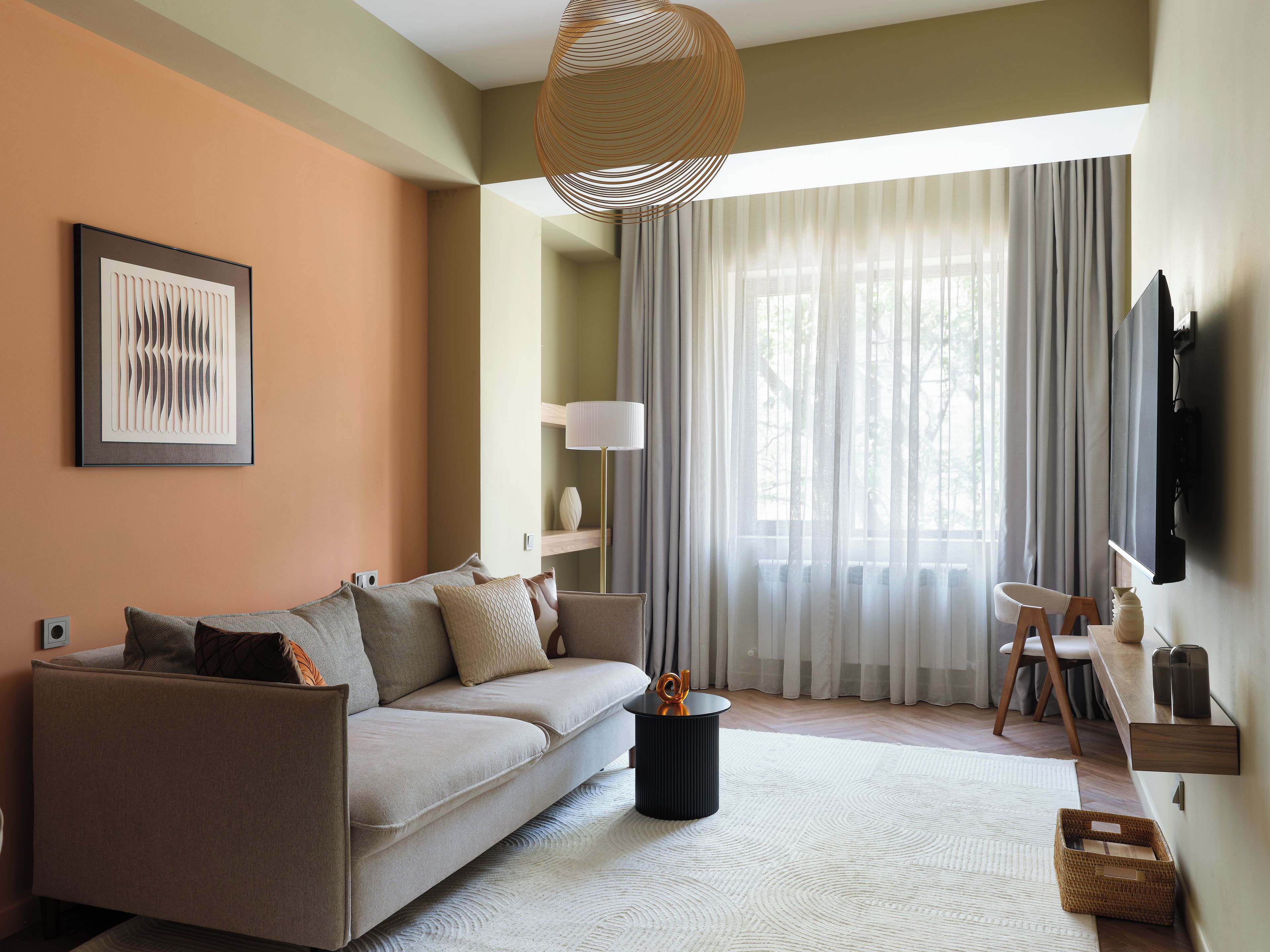 Ein modernes Wohnzimmer mit Sofa, Stehlampe, Fernseher und einem großen Fenster mit Vorhängen.